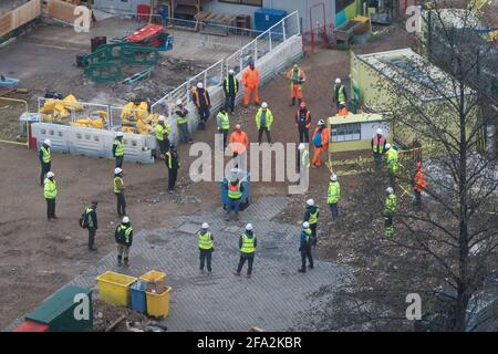 construction workers having a physically distanced team meeting on site Stock Photo