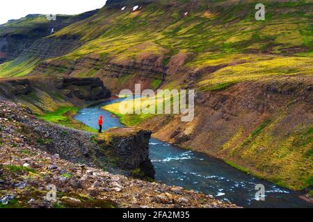 Hiker standing at the edge of the Laxa i Kjos river near Reykjavik in Iceland Stock Photo