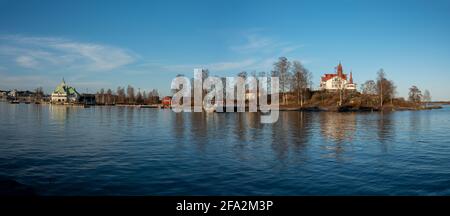 Helsinki / Finland - APRIL 18, 2021: A panoramic view of an island with old wooden cottages in the middle of a city center during sunset. Stock Photo