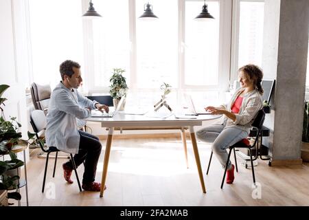 Confident business partners working together on new strategy for the company, smiling. Successful colleagues learning financial graphs to making a Stock Photo