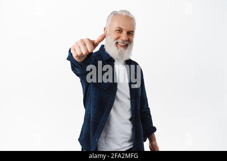 Yes very good. Happy stylish senior man showing thumb up with extended hand, praising you, great job, excellent choice gesture, being proud and Stock Photo