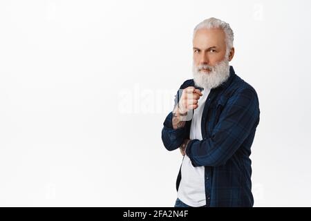 Serious old man with tattoos pointing finger at camera and frowning, inviting you, scolding grandchildren, being a boss, choosing someone, standing Stock Photo