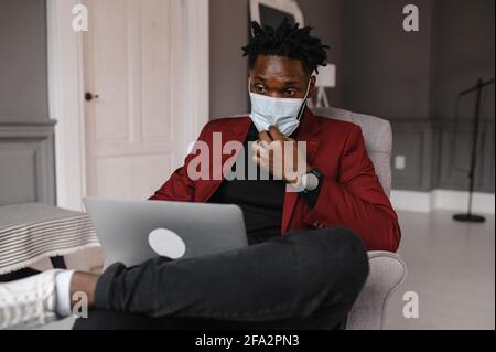 Handsome Black African American Man Working from Home and Having Video Call on Laptop Computer while Sitting on a Sofa in Living Room Stock Photo