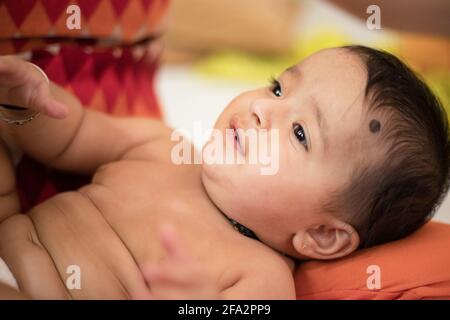 Closeup shot of a cute happy Indian female baby wearing a hat with fake hair Stock Photo