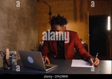 Handsome Black African American Man Working from Home and Having Video Call on Laptop Computer while Sitting on a Sofa in Living Room Stock Photo