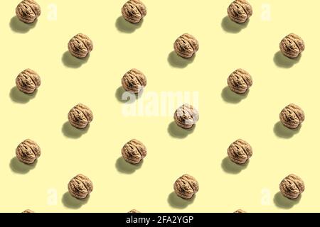 The whole unpeeled walnuts pattern on yellow background. A trendy hard light, dark shadow, flat lay, mockup, template Stock Photo