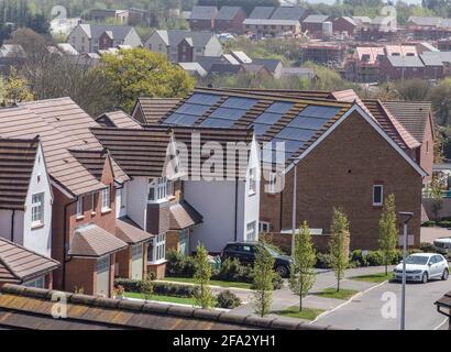 Looking across the roofs of new build houses at Pinhoe Exeter, Devon, with solar panels visible and building site in the distance. New home building, Stock Photo