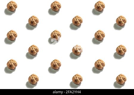 The whole unpeeled walnuts pattern isolated on white background. A trendy hard light, dark shadow, flat lay, mockup, template Stock Photo
