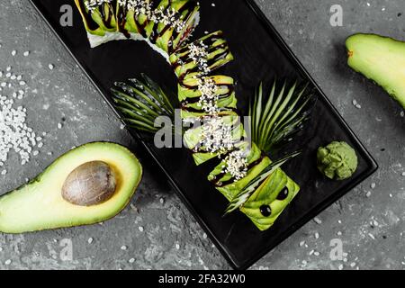 Green dragon sushi roll with eel, avocado, cucumber and ginger, accompanied with fried tempura shrimp. Traditional asian rice sushi healthy seafood Stock Photo