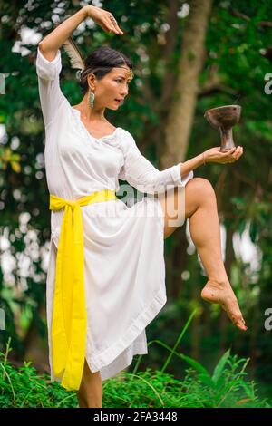 young attractive and happy Asian woman outdoors at green rice field landscape with chalice dancing doing spiritual meditation and traditional ritual d Stock Photo