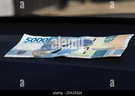 50000 Indonesian Rupiah currency and some Rupiah coins, on the dark table Stock Photo