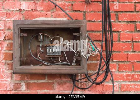 Niche of an old broken electrical panel on the background of an old red brick wall texture. Stock Photo