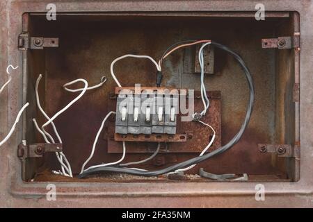 Niche of an old broken abandoned electrical industrial panel with wires, close up. Stock Photo