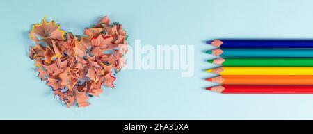banner with sharpened colored pencils and heart-shaped pencil shavings on pastel blue color. Rainbow or LGBT pencils. Decoration for St. Valentine's D
