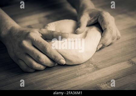 Woman kneads bread dough on a wooden pastry board Stock Photo