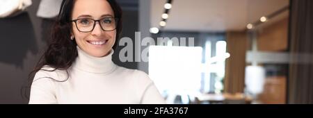 Brunette woman with glasses smiling and holding ballpoint pen over notebook Stock Photo