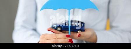 Female hands holding toy car and umbrella close-up Stock Photo