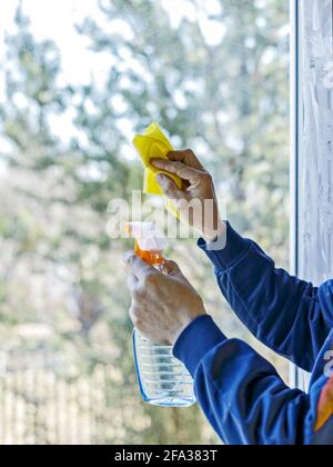 Man wipes glass window using spray. Stock Photo