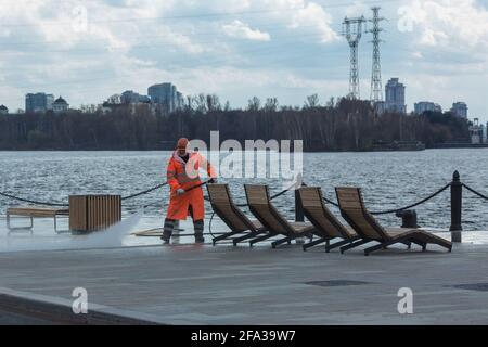 Moscow, Russia - April 22 2021: City worker cleaning the embankment using high pressure water equipment. Stock Photo