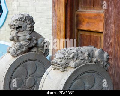 Classic, traditional stone carved Chinese dragon statues guard a wood door. At the Zhishan Garden in Taipei, Taiwan. Stock Photo
