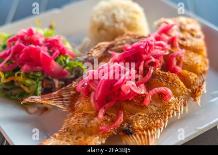 Fried fish platter in Mexico, with rice, vegetables and red onion, selected focus Stock Photo