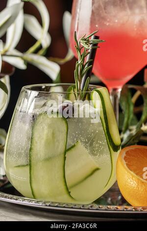 Gin tonic cocktail with cucumber, berries and rosemary on silver tray Stock Photo
