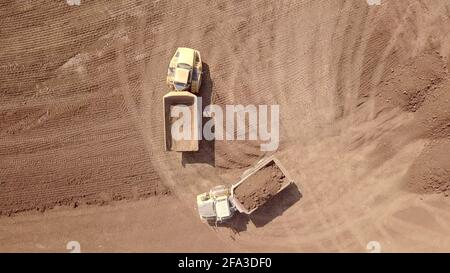 Heavy duty dump truck loaded with soil in a new construction site. Aerial view. Stock Photo