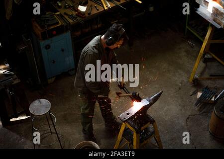 Traditional metalworking process in a forge.The master blacksmith works in the workshop. Top view.Traditional metalworking process in a forge. Stock Photo