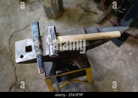 Tools for forging in a blacksmith shop. The hammer lies on the anvil. Top view. Stock Photo