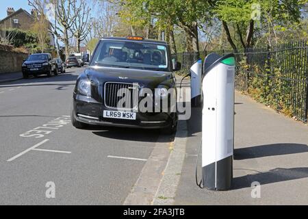 Kerbside electric vehicle charging points on Elmwood Rd in Dulwich, London, UK. Shows new LEVC TX plug-in hybrid electric taxi connected and charging. Stock Photo