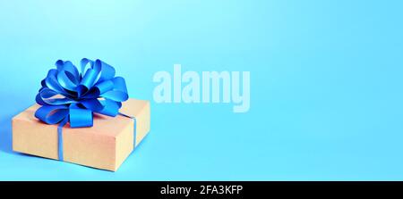 Cardboard gift box with purple bow on blue background. Stock Photo