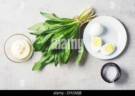 Bunch of fresh ramson (wild garlic), mayonnaise sauce, eggs. Ingredients for a salad or appetizer. Stock Photo