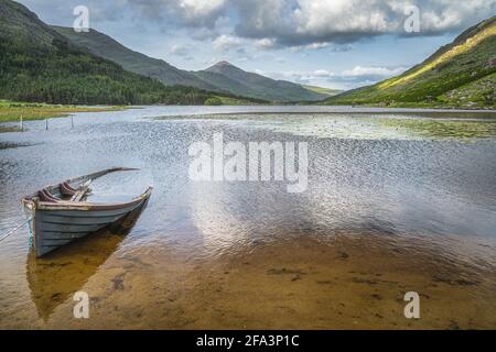 Sunken or half submerged paddle boat in Lough Gummeenduff with view on beautiful Black Valley, MacGillycuddys Reeks mountains, Ring of Kerry, Ireland Stock Photo