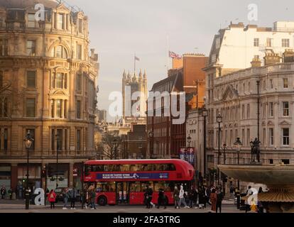 London, Greater London, England - Apr 17 2021: Double Decker bus near Trafalgar Square with the Houses of Parliament in the background and Union Jacks Stock Photo