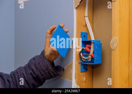 Hands of an electrician fasten the electrical box to the beams to place Stock Photo