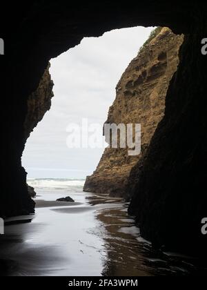 from darkness of Piha Blowhole cave to ocean Stock Photo
