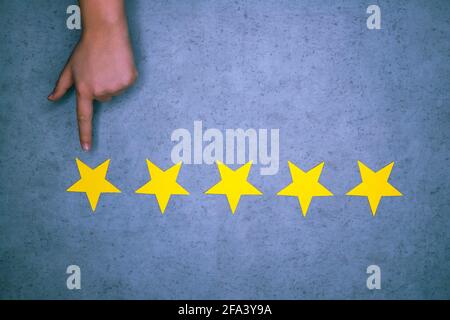 hand on blue background points to yellow star. symbol of rating assignment, satisfaction with service. Stock Photo