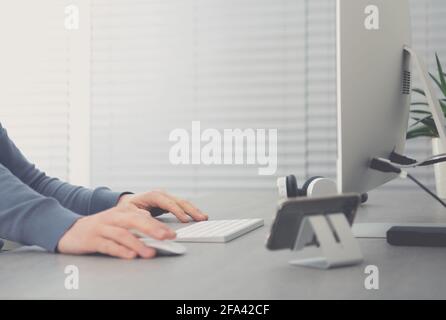 Men Behind Office Desk Working on His Desktop Computer. Left Top Copy Space Area. Corporate Theme. Clean and Elegant Office Interior. Stock Photo