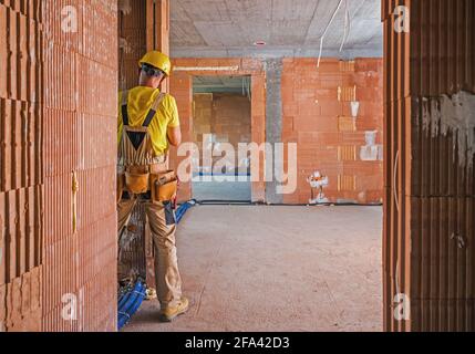 Professional Construction Worker Inside Brick Built Building Finishing Wall Elements. Construction Industry Theme. Stock Photo