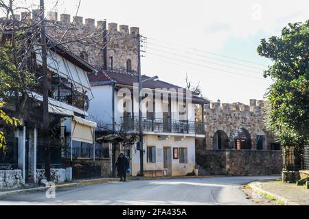 Small mountains village built against castle like walls with old person walking along sidewalk up in the Taygetus Mountain Range in the Peloponnese pe Stock Photo