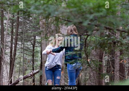 Two high school freshman girls enjoy their friendship together out in nature in the woods Stock Photo
