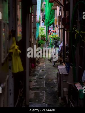 Daytime view of a bicycle in a cluttered alleyway between apartment buildings in Fukushima City, Japan Stock Photo