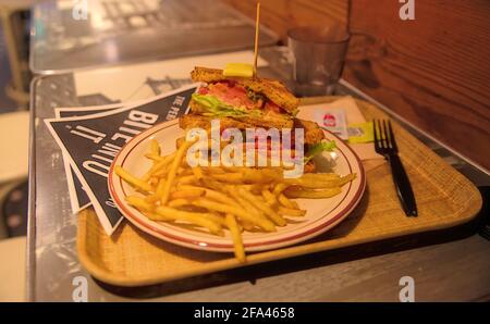 A gourmet toasted BLT sandwich with shoestring french fries on a table in a restaurant Stock Photo