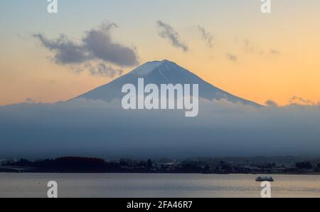 Late afternoon view of a partially fog-shrouded Mount Fuji and Lake Kawaguchi under a colorful sunset sky Stock Photo