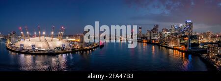 The O2 arena and Canary Wharf London, aerial view at dusk looking over the river thames. Panoramic drone photograph at blue hour showing city lights Stock Photo