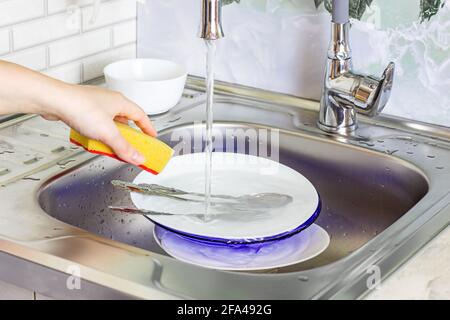Metal sink in the kitchen full of dirty dishware stack. Housework, washing dishes, household duties concept. Stock Photo