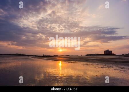 Beautiful view of the sunset piercing through the cloudy sky on the coast Stock Photo