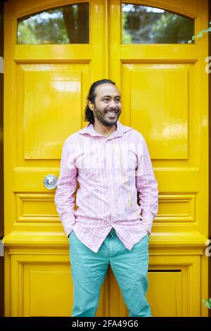 smiling young hispanic man listening to music on a colorful street Stock Photo