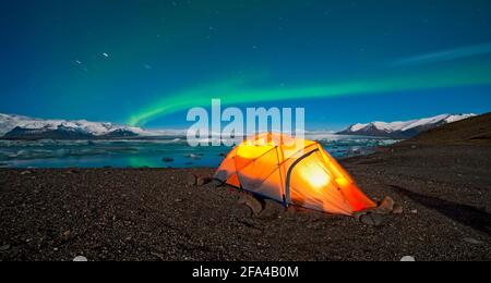 illuminated tent in the Arctic with Northern Lights in the sky Stock Photo