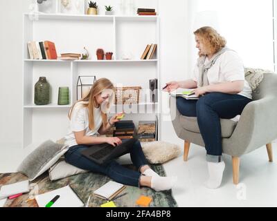 two blond women studying at home laptop and notebooks Stock Photo